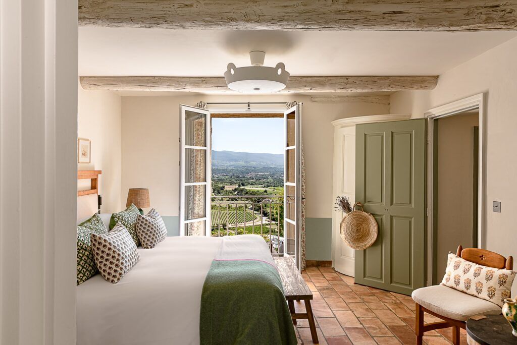 French bedroom with throws and a door opening to the countryside