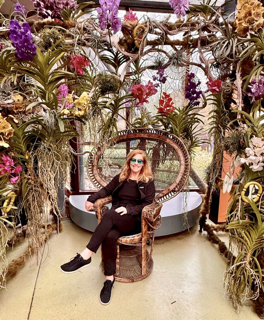 photo of me in a chair surrounded by flower sin the Beatrix Pavilion