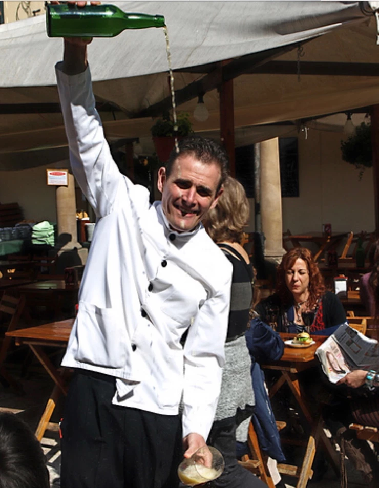 a waiter pouring cider, performance art style,  in Oviedo Spain, the capital of Asturias