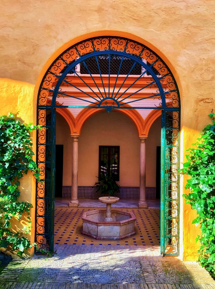 a beautiful orange hued doorway in the Alcazar Gardens in Seville