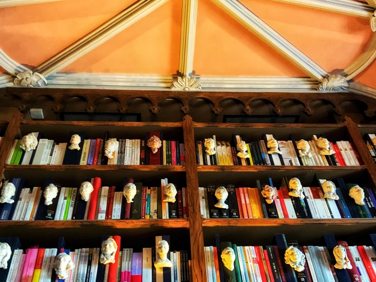 mini busts of writers adorning books in the upper shelves