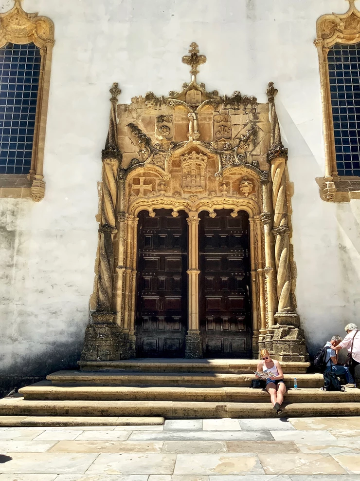 my daughter lounging outside the chapel's Manueline door while we wait to enter the library