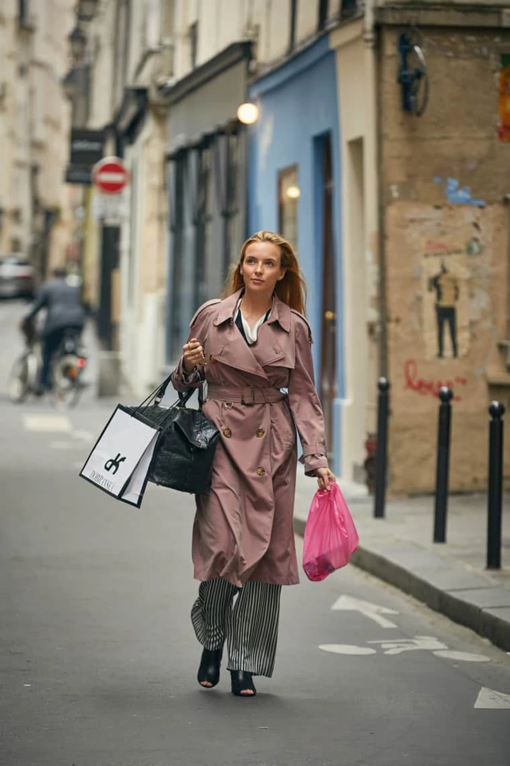 Villanelle goes on a shopping spree following a successful kill in Vienna, dressed in a Burberry Mac coat, Lanvin blouse, and Balenciaga boots.