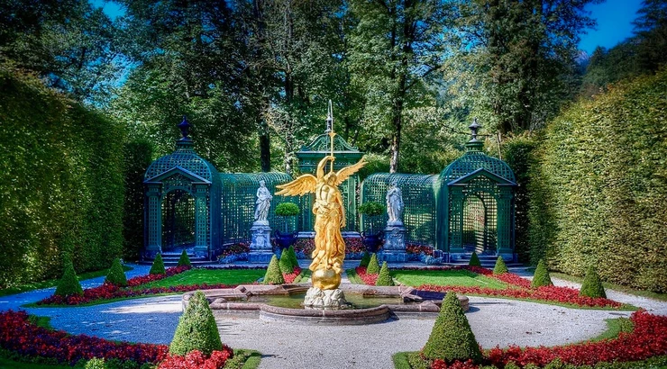 gold statue of the Roman goddess Fama in the eastern gardens, with a bust of Louis XIV behind her