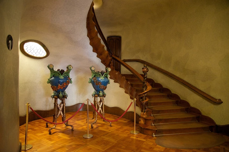 the spiny wooden staircase flanked by two Gaudi designed vases