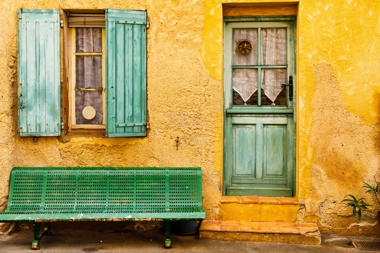 an ochre colored house with faded green shutters in Roussillon