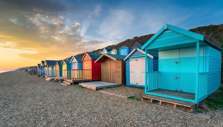 sunset over a row of brightly coloured beach huts at Milford on Sea in NH