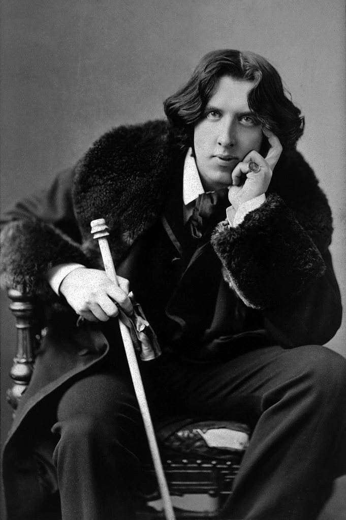 the novelist and playwright Oscar Wilde, in a languid pose in his famous velvet jacket