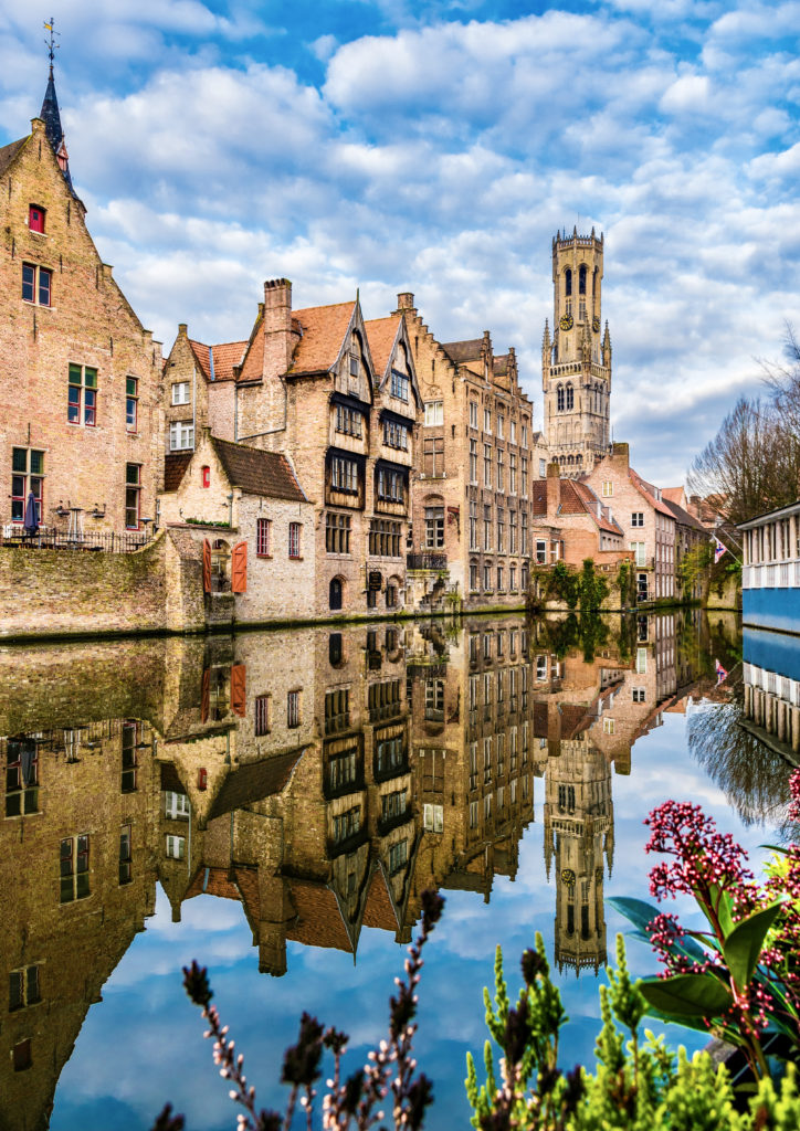 medieval buildings and the bell tower along a canal in Bruges