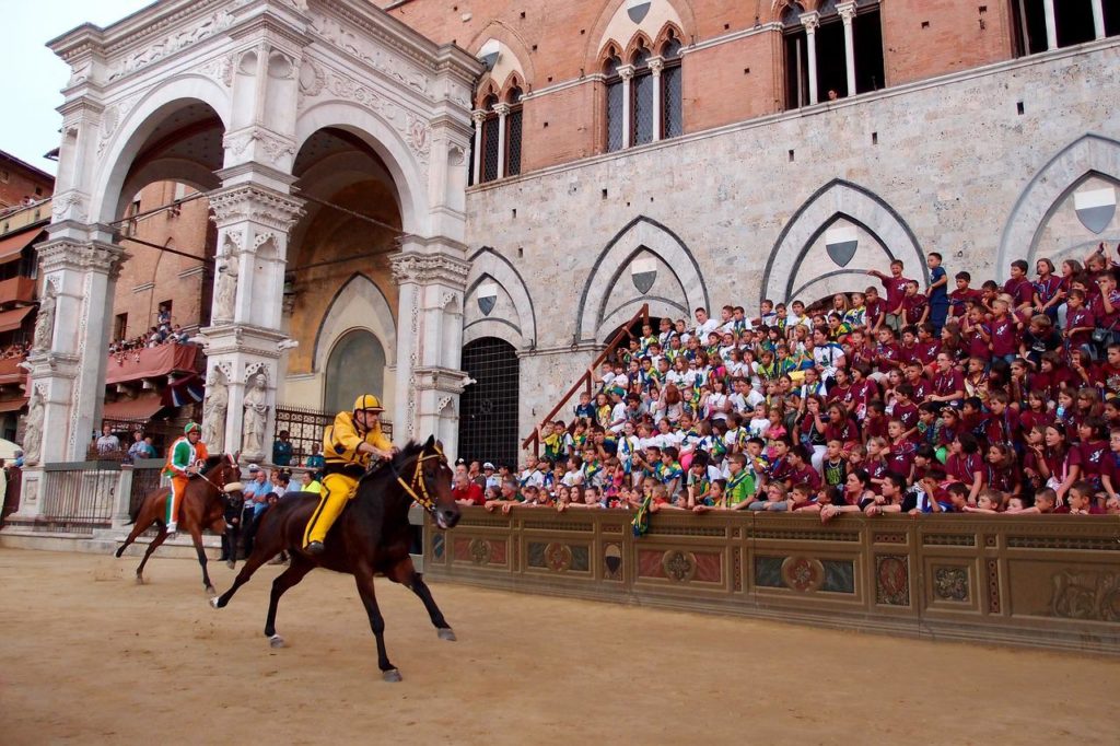 a jockey and horse racing past the Palazzo Pubblico