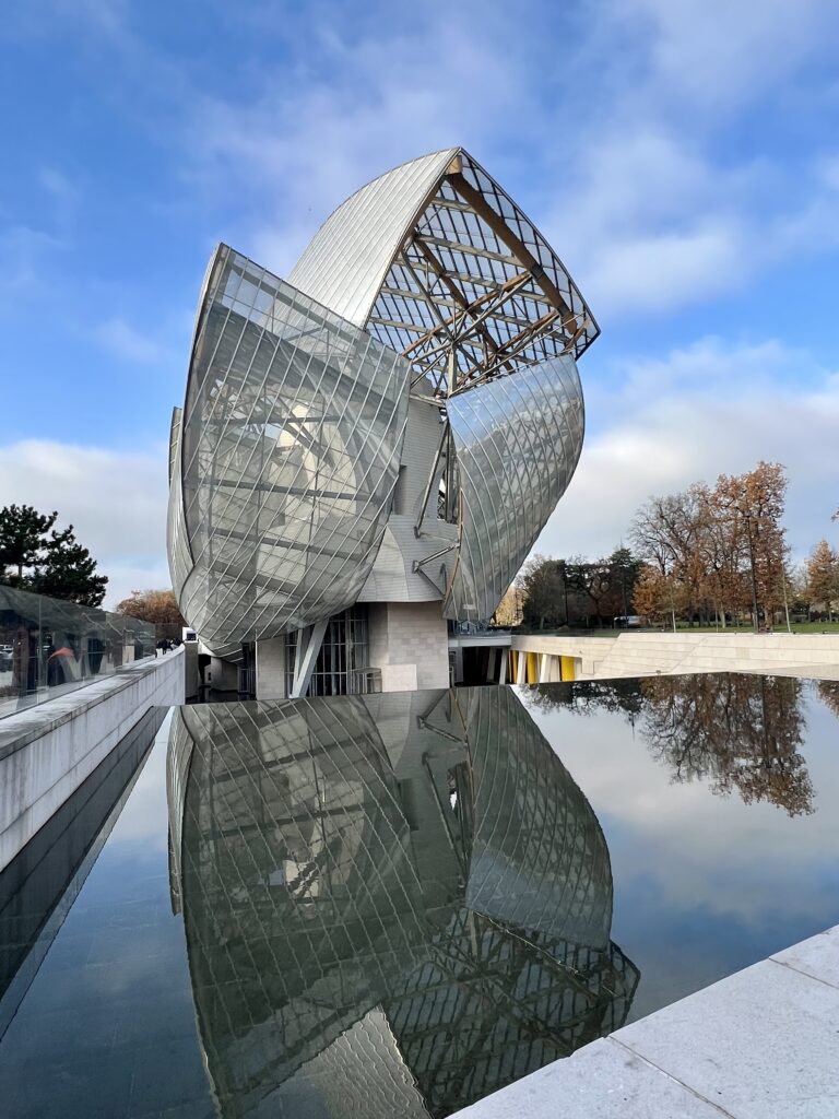outer facade of Fondation Louis Vuitton, with building reflecting in the fountain