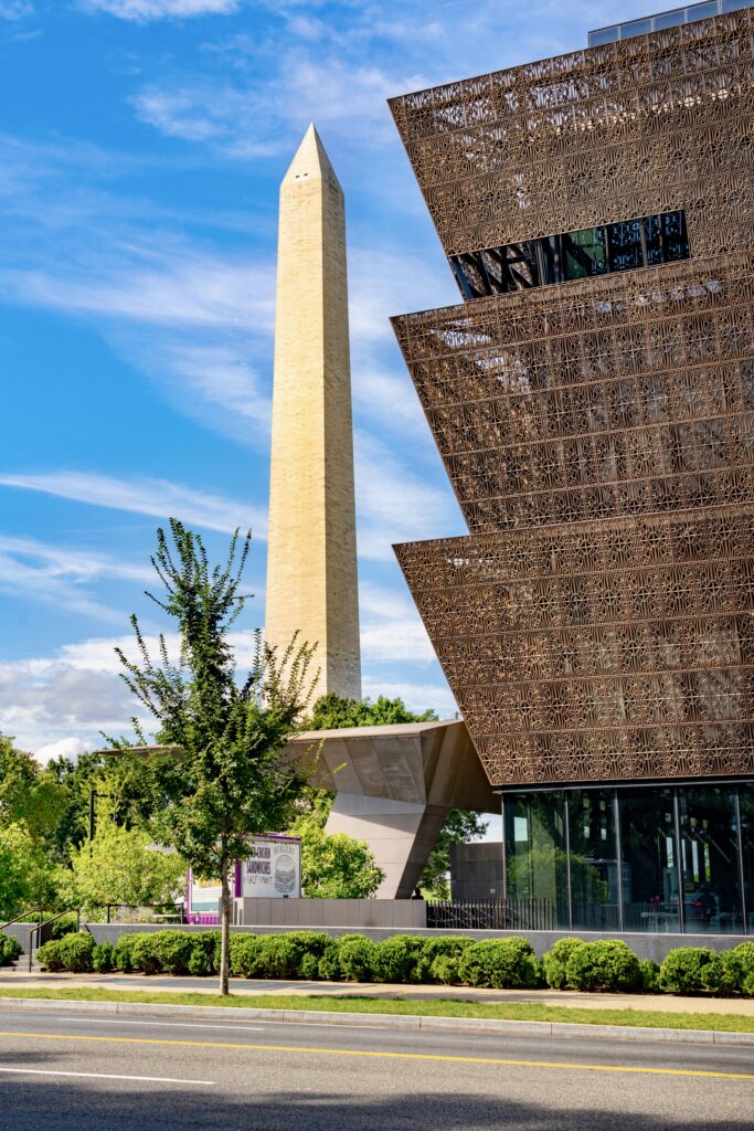 facade of the National Museum of African American History and Culture, with the Washington Monument in the background 
