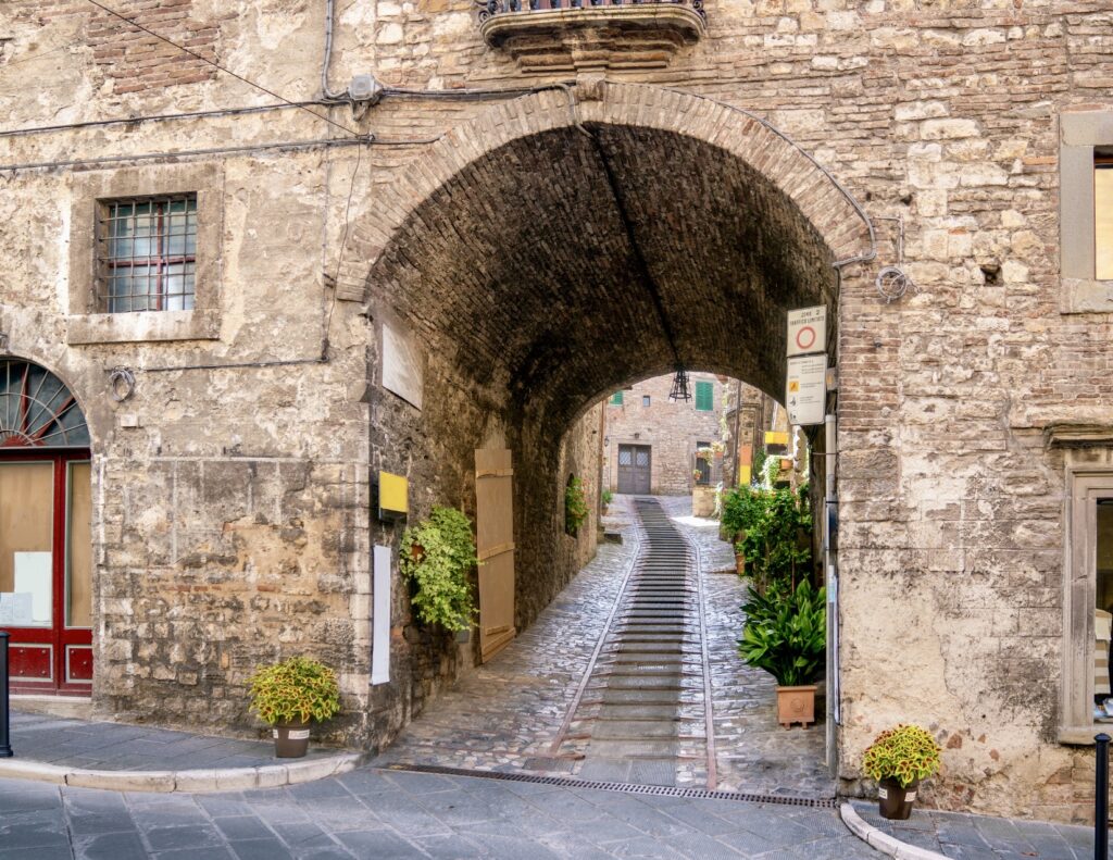 little lane with a staircase under an arch in Spello