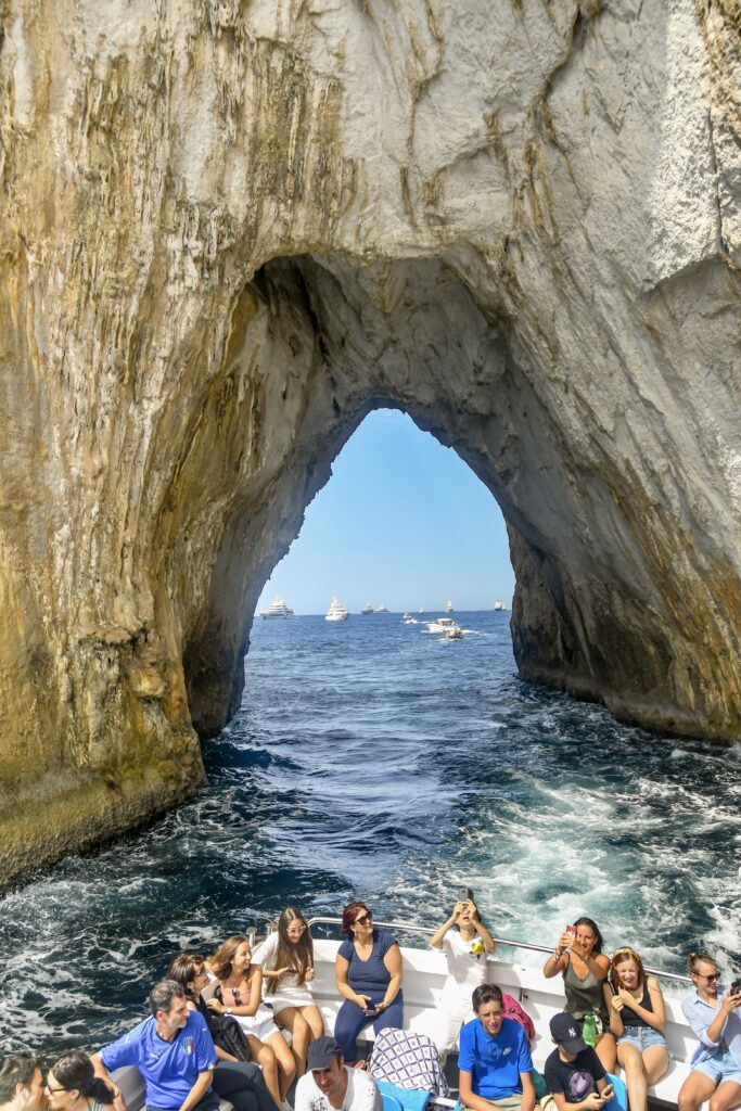 people on a boat tour going through an arch in the rocks