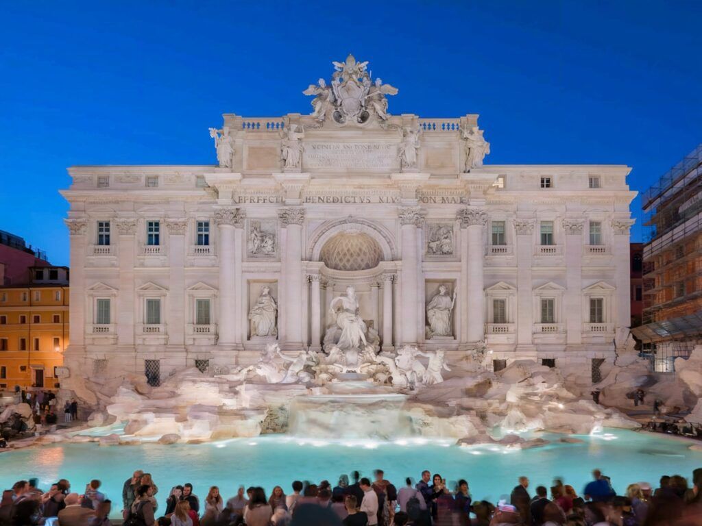 Trevi Fountain with crowds around it at night