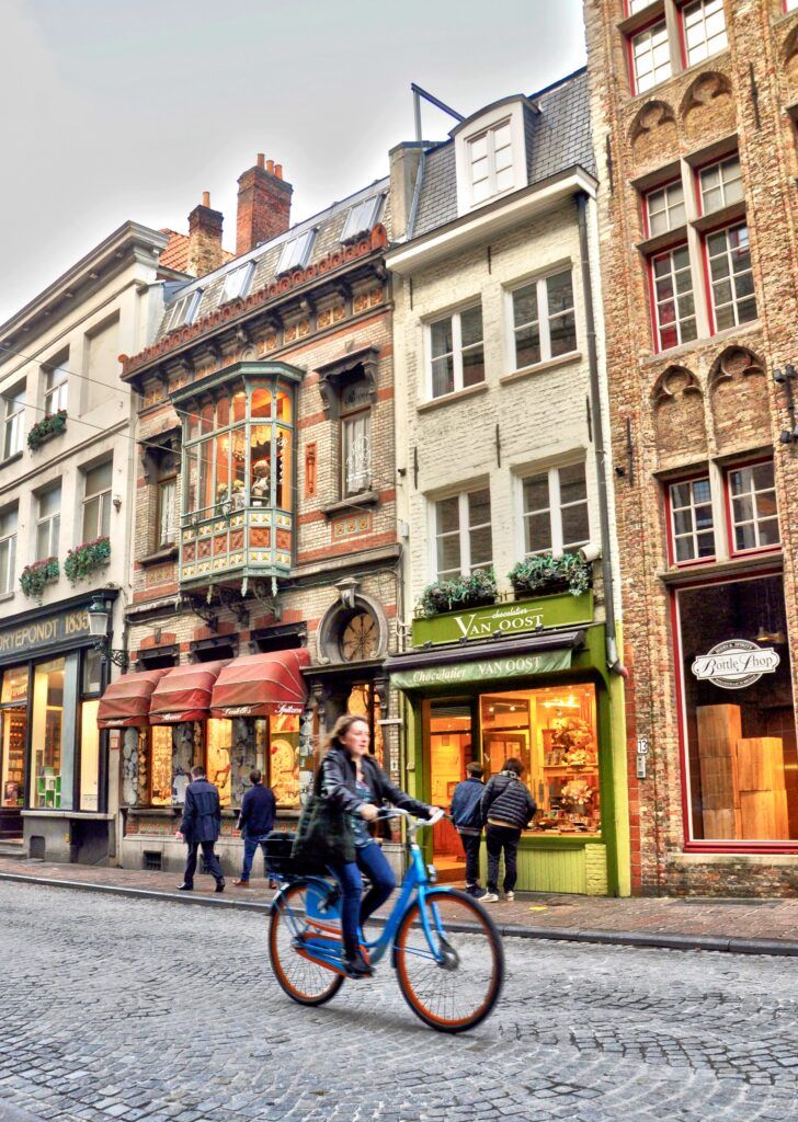 woman on a bike with beautiful Flemish architecture