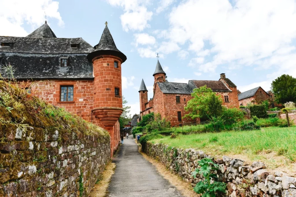 a tree with red stone buildings in Collonges-la-Rouge