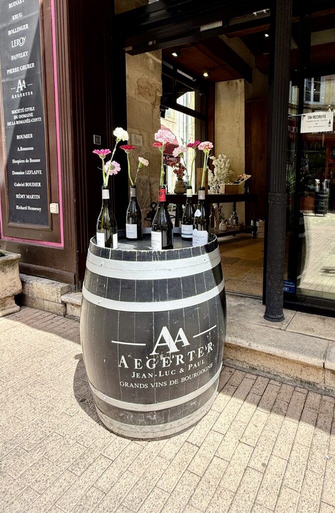 in shop with a barrel outside with flowers in wine bottles