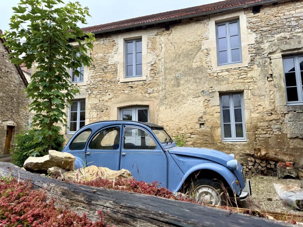 stone house with blue shutters and a blue car in front
