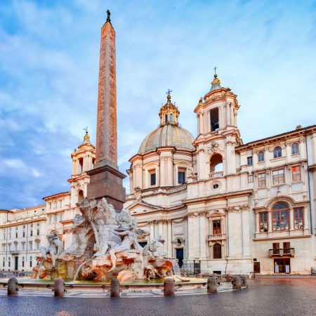 Fountain of the Four Rivers with an Egyptian obelisk and Sant Agnese Church on the famous Piazza Navona Square in the morning, Rome, Italy.